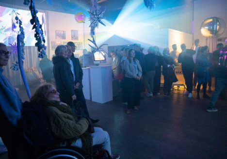 Ausstellungsbesucher in einem halbdunkeln Raum. Licht von Projektionen. Mystische Atmosphäre.
