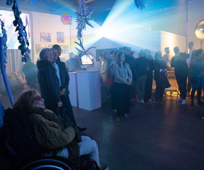 Ausstellungsbesucher in einem halbdunkeln Raum. Licht von Projektionen. Mystische Atmosphäre.